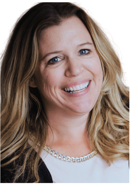 A smiling woman with long, wavy hair wearing a light-colored top and a chain necklace, facing the camera against a white background.
